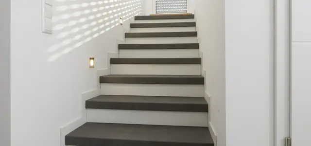 Escalier pris entre deux murs effet béton ciré gris et contremarches blanches éclairage par LED intégré au mur