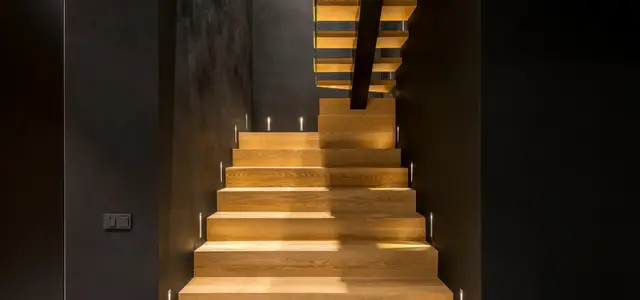 escalier moderne en bois dans une cage d'escalier noir avec éclairage intégré