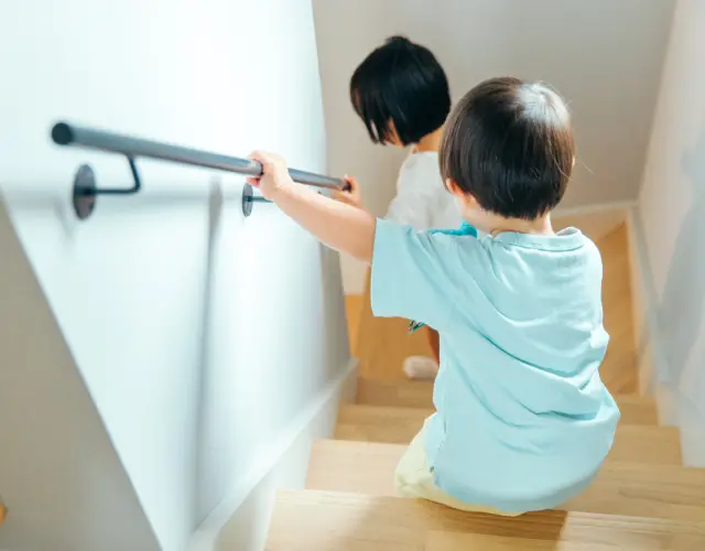 Deux jeunes enfants descendant un escalier en bois équipé d’une main courante murale pour plus de sécurité